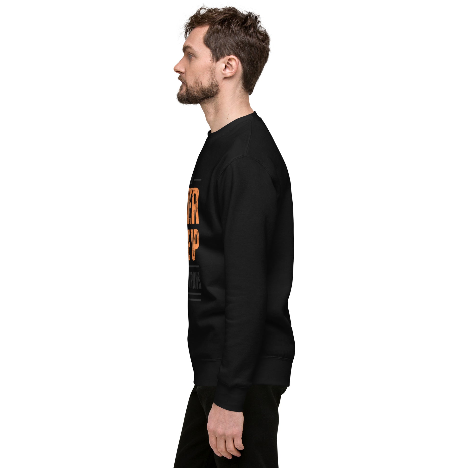 A man with short brown hair and a beard stands in profile facing left, wearing the Never Give Up Unisex Premium Sweatshirt with orange and white text on the front, showcasing contemporary streetwear style against a plain white background.