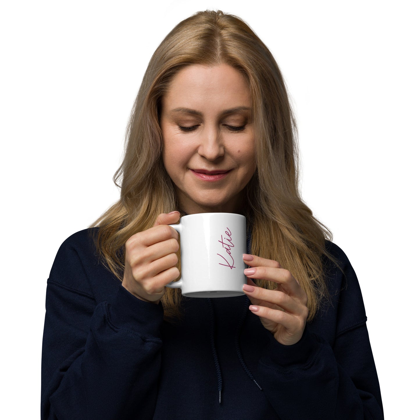 A woman with long blonde hair in a black sweatshirt smiles softly while holding the White glossy mug, featuring the name Katie in pink script. The dishwasher safe mug is set against a plain white background.